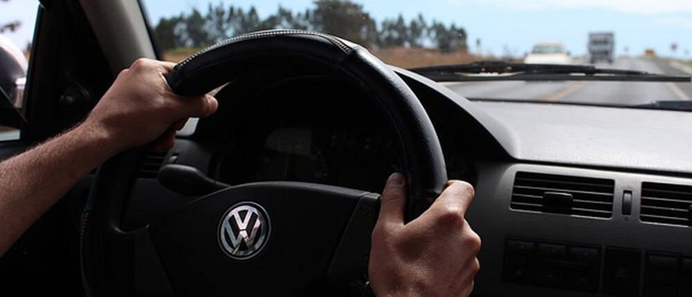 The inside POV of someone with both hands on the wheel while driving to prevent losing control of the vehicle.