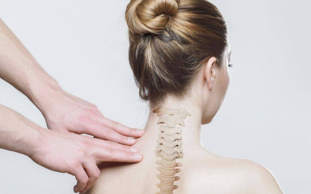 A doctor putting his hands on a female patient's upper back to assess Spine and Soft Tissue Injuries, with an animation of her spine in the middle.